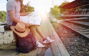 young man traveler with backpack and hat at the train station wi