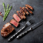 Grilled sliced beef steak on stone table. Top view